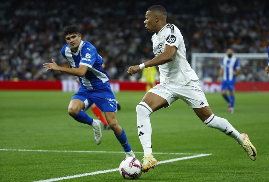 El delantero francés del Real Madrid, Kylian Mbappé (d), conduce el balón ante un defensor del Alavés