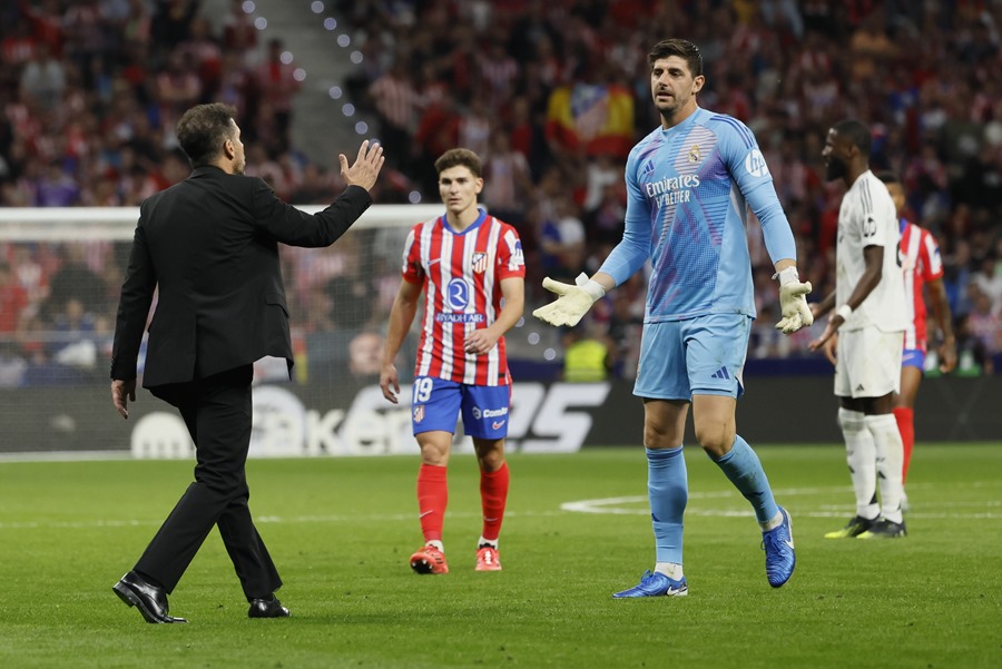 El portero del Real Madrid Thibaut Courtois (d) conversa con el entrenador del Atlético, Diego Simeone (i),