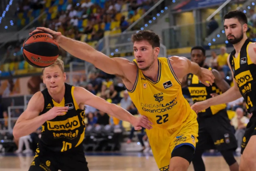 El pívot del Dreamland Gran Canaria Ethan Happ (c) disputa un balón a los jugadores del Lenovo Tenerife Sasu Salin (i) y Bruno Fitipaldo (d) durante el segundo y definitivo partido de la Copa Isola. EFE/Ángel Medina G.